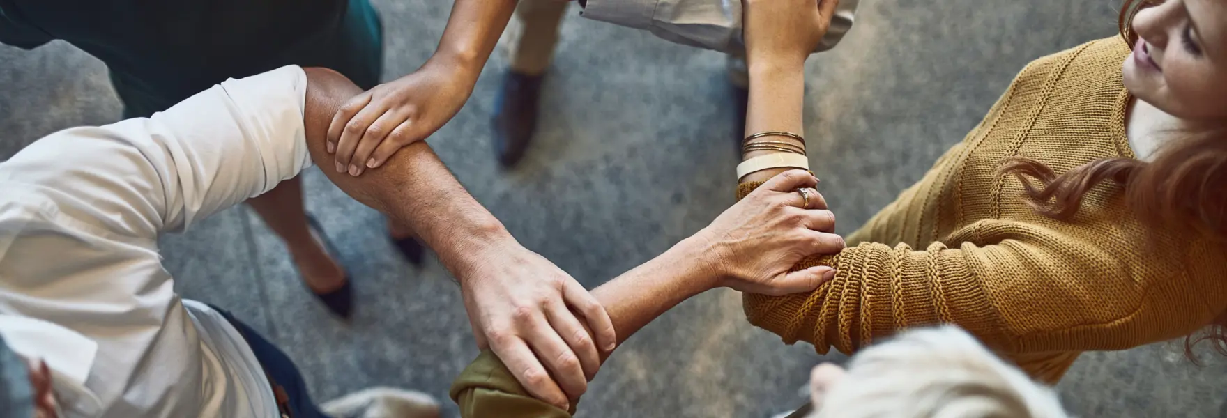 Persone in cerchio che si tengono per le braccia in segno di coll